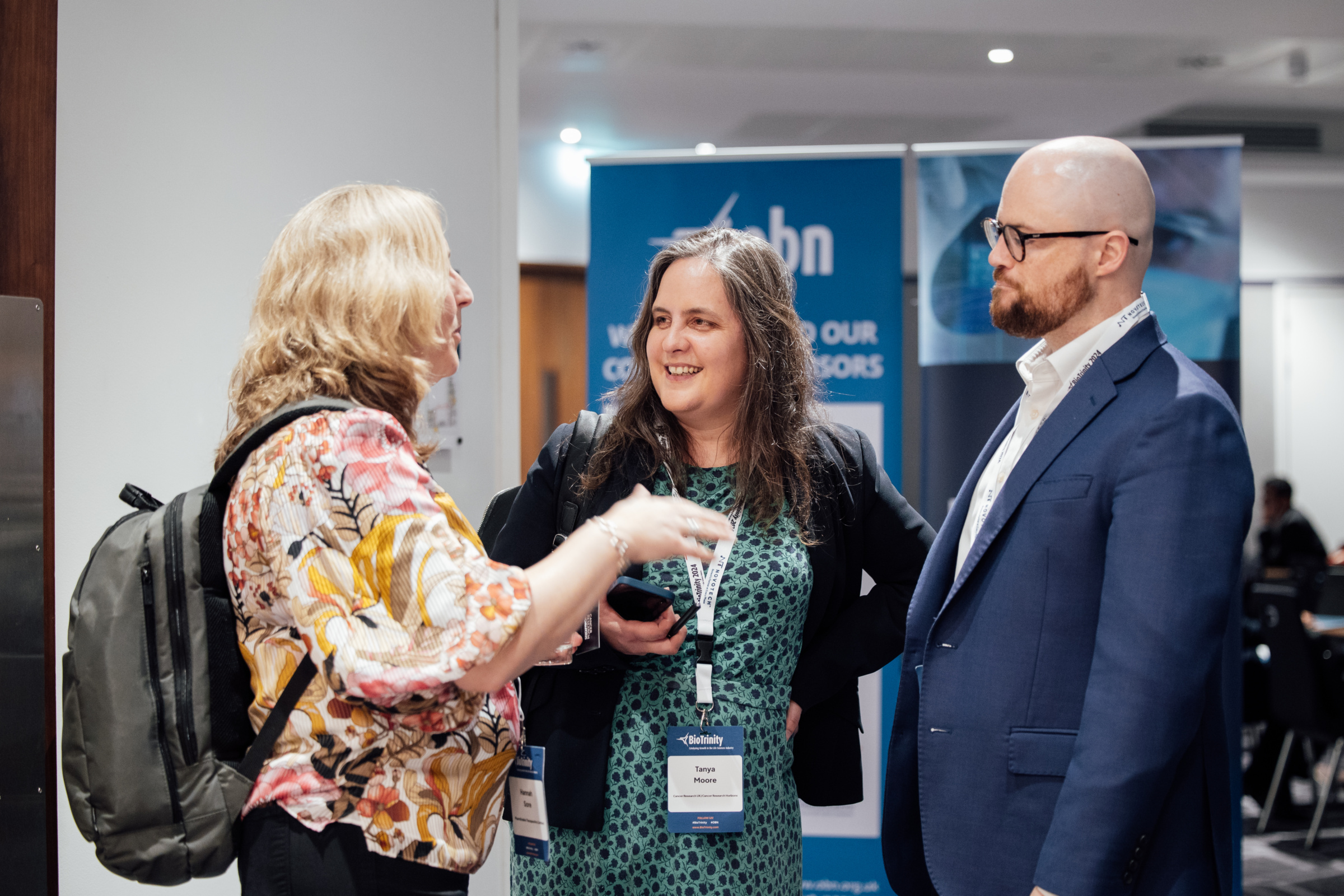 Photograph showing three people having a discussion in the networking area of a conference.